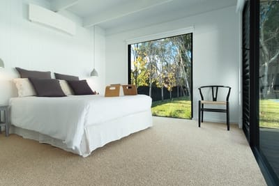 A bedroom, brightly lit with natural light. The carpet is Bramble, from the Brit range. It's a warm beige colour.