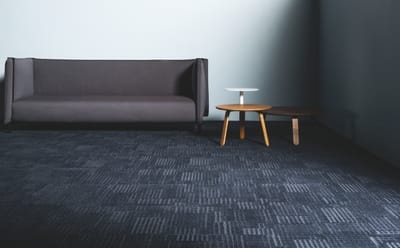 A lounge and coffee tables in a room with light blue walls. The carpet tiles are Bliss from the Chakra range.